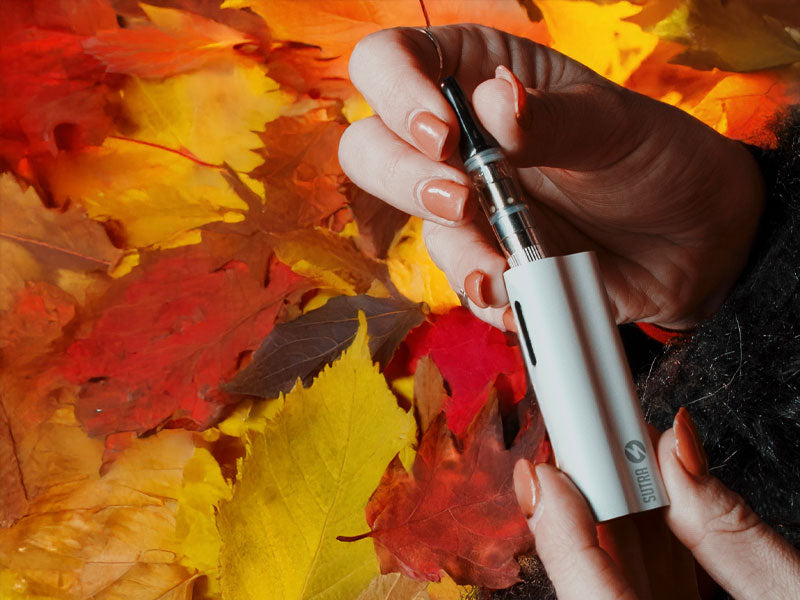 Woman in coat holding the Sutra Auto with fall leaves in background