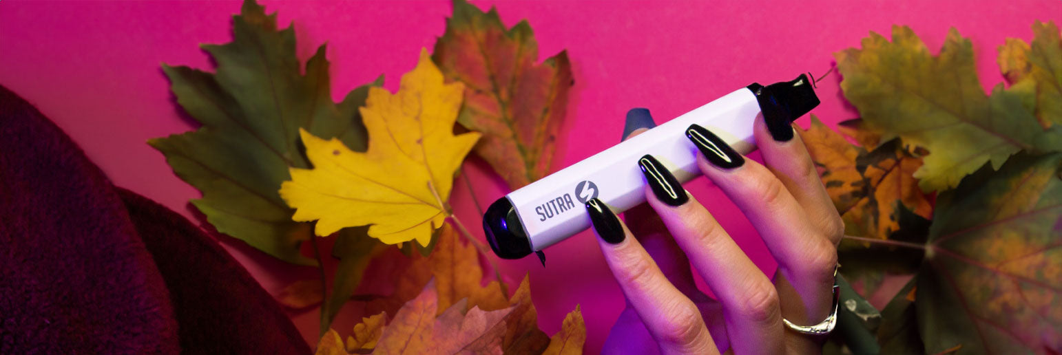 woman with black nails holding the Sutra SILO with fall leaves and pink background